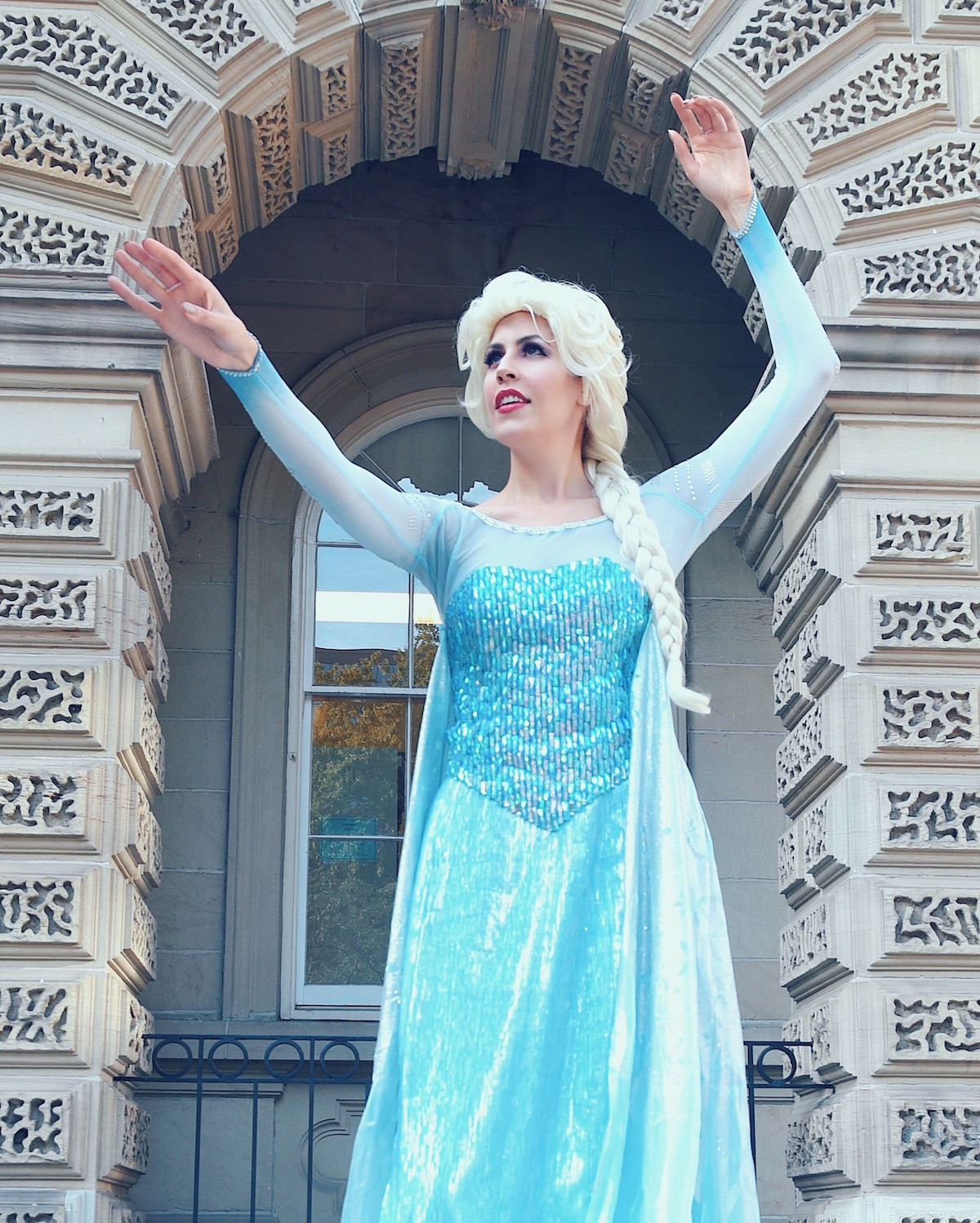 Elsa has her hands raised and looking toward the Frozen flurry she's about to create